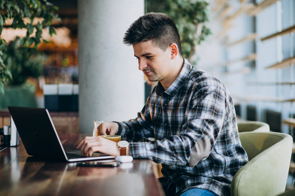 Young handsome business man using laptop in a cafe
